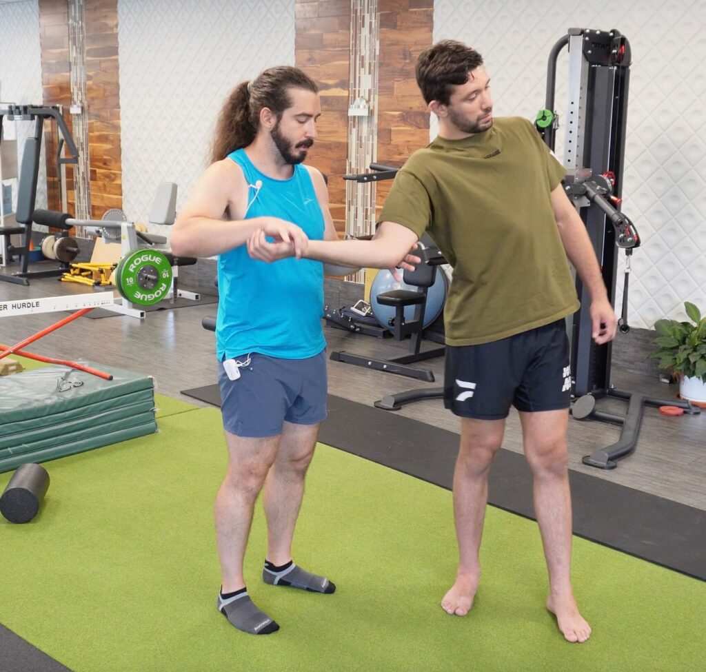 Dr. John holding Rene's right arm and Rene turning his body and shoulder to demonstrate bjj armbar mobility